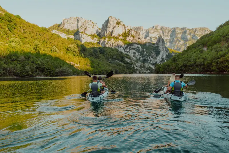 A group of friends enjoying having fun and kayaking while exploring the calm river, surrounding forest and large natural river canyons